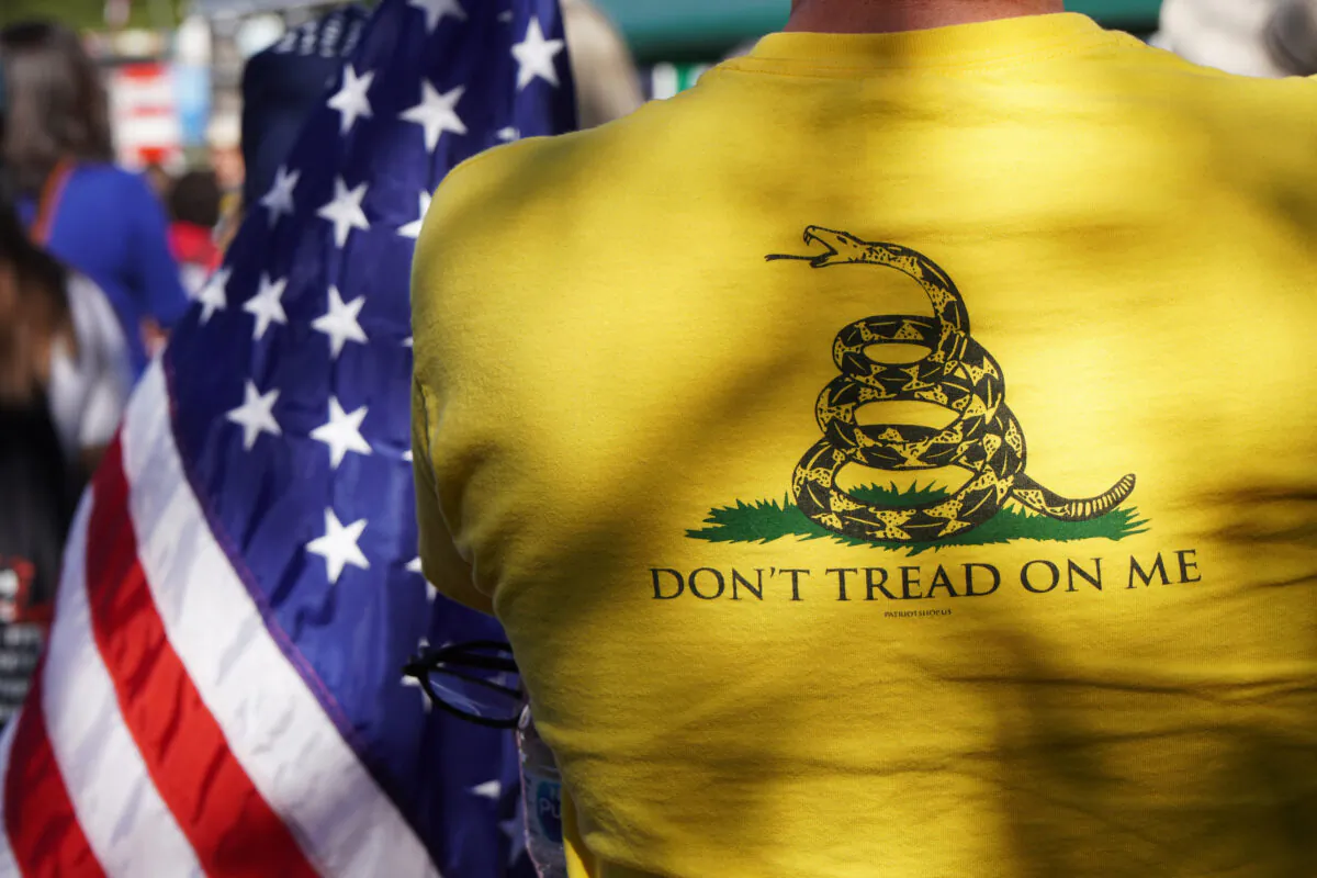 A protester wearing a “Don’t Tread on Me” Gadsden Flag T-shirt listens to a speaker at a rally in support of medical freedom in Phoenix, Ariz., on Nov. 3, 2021. (Allan Stein/Epoch Times)