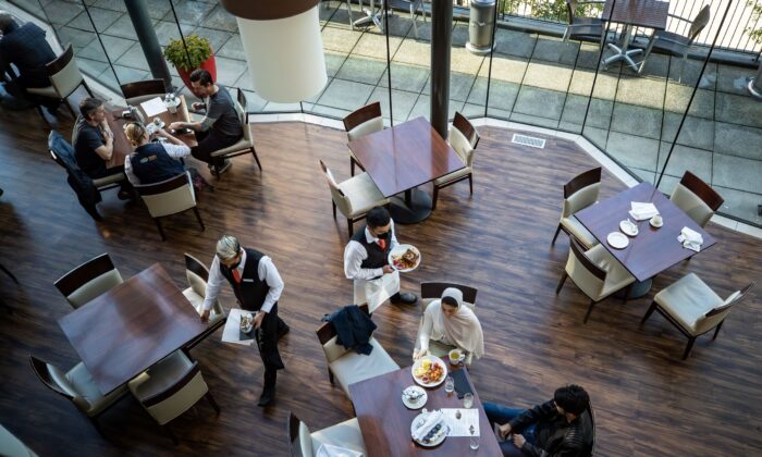 A server brings food to a table as people dine at a restaurant in Vancouver on Sept. 21, 2021. (Darryl Dyck/ Canadian Press)