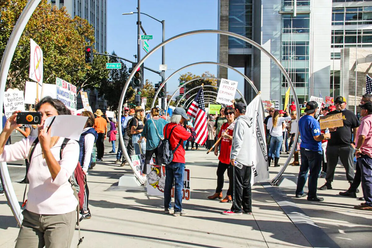 People hold signs and flags in front of San Jose City Hall to protest vaccine mandates on Nov. 3, 2021. (David Lam/The Epoch Times)