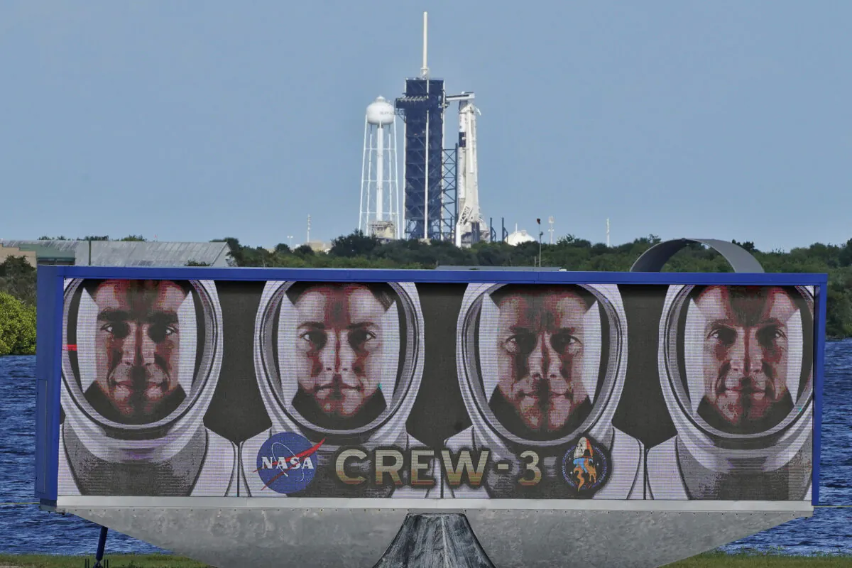 Crew-3 astronauts, from left, Raja Chari, Kayla Barron, Matthias Maurer, of Germany, and Tom Marshburn, are shown in their official portraits as a SpaceX Falcon 9 rocket with the crew dragon capsule attached sits on Launch Pad 39-A at the Kennedy Space Center in Cape Canaveral, Fla., on Oct. 29, 2021. (Chris O'Meara/AP Photo)