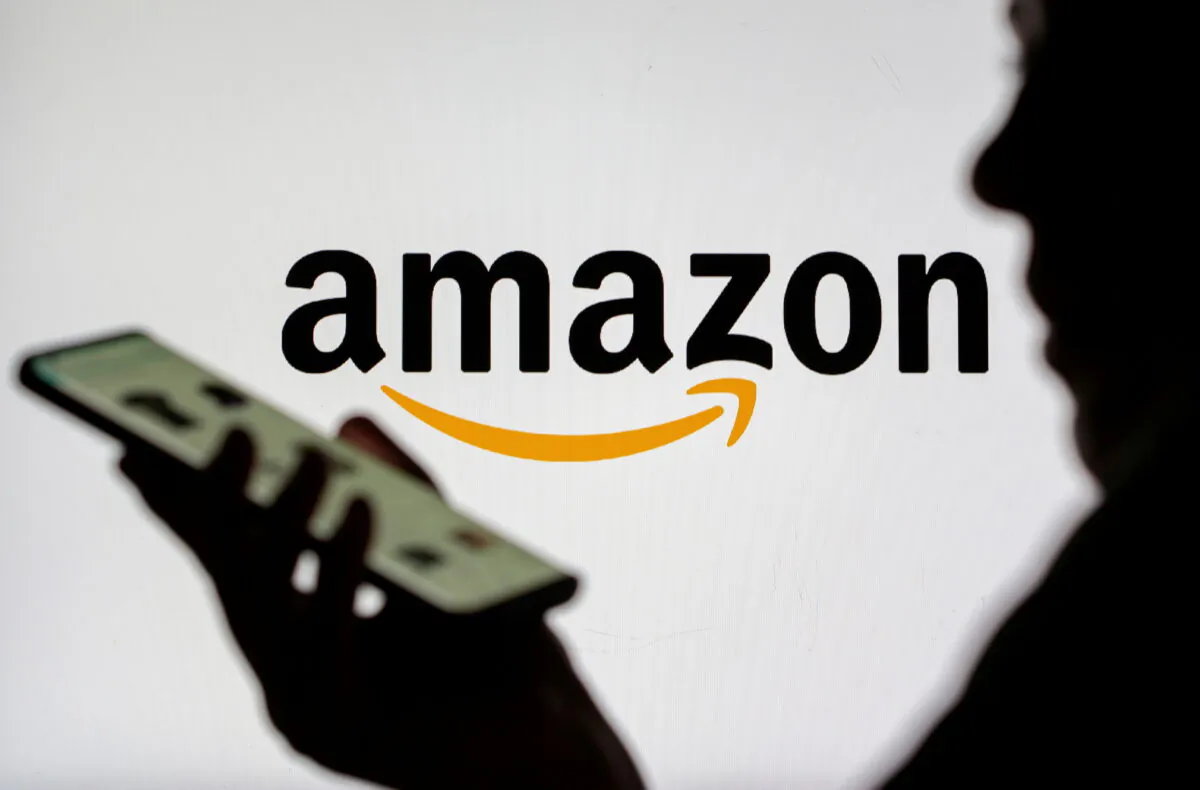 Woman with smartphone is seen in front of displayed Amazon logo in this illustration taken on July 30, 2021. (Dado Ruvic/Illustration/Reuters)