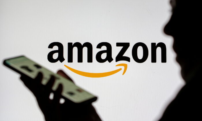 Woman with smartphone is seen in front of displayed Amazon logo in this illustration taken on July 30, 2021. (Dado Ruvic/Illustration/Reuters)