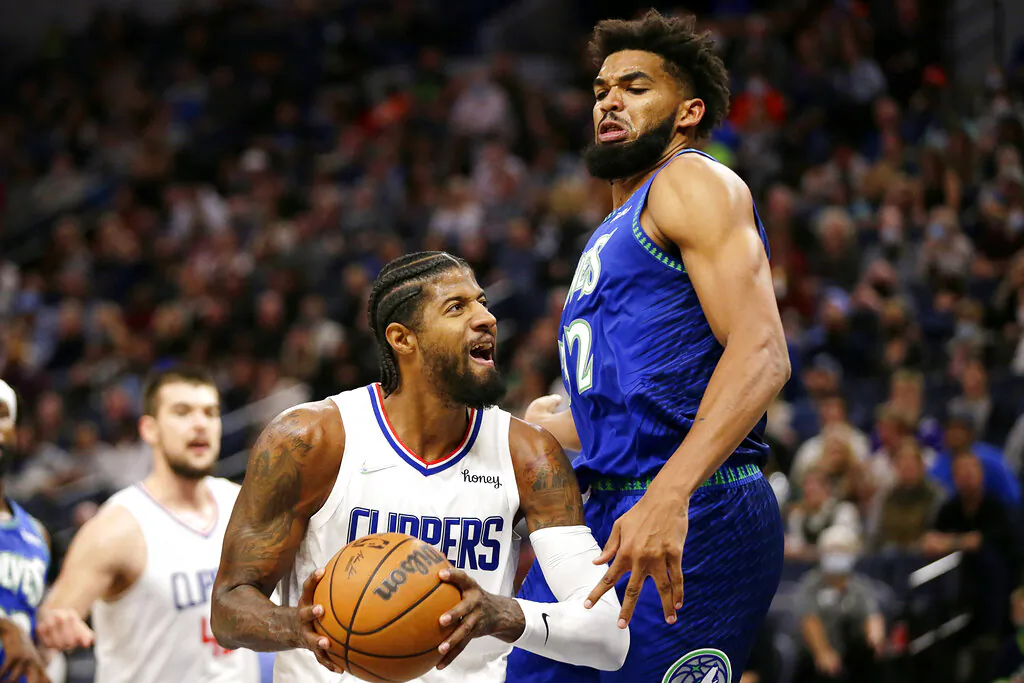 Los Angeles Clippers guard Paul George (L) drives on Minnesota Timberwolves center Karl-Anthony Towns during the first half of an NBA basketball game in Minneapolis, Minn., on Nov. 5, 2021. (Andy Clayton-King/AP Photo)