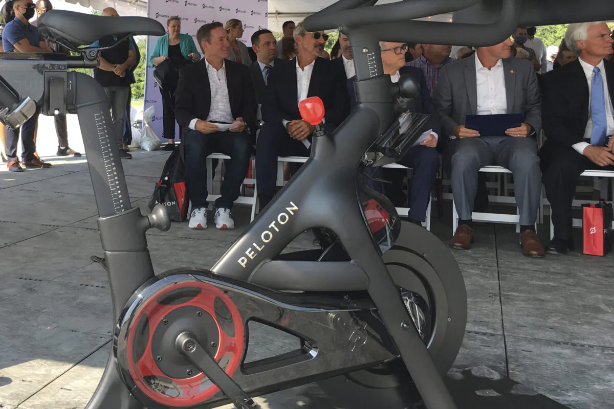 Peloton CEO John Foley (L) is seen behind one of his company's fitness machine along with others gathered for the groundbreaking for the company's first U.S. factory in Luckey, Ohio, on Aug. 9, 2021.  (John Seewer/AP Photo)