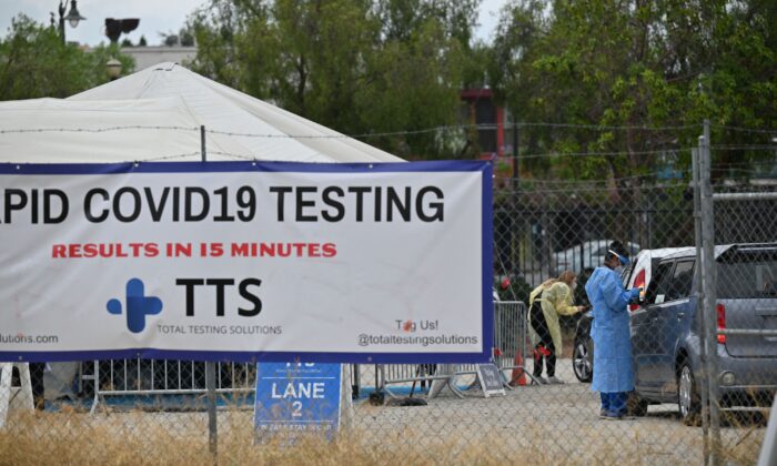 Healthcare workers collect information from people arriving for COVID-19 tests, at a testing site in Los Angeles, Calif., on July 18, 2021. (Robyn Beck/AFP via Getty Images)