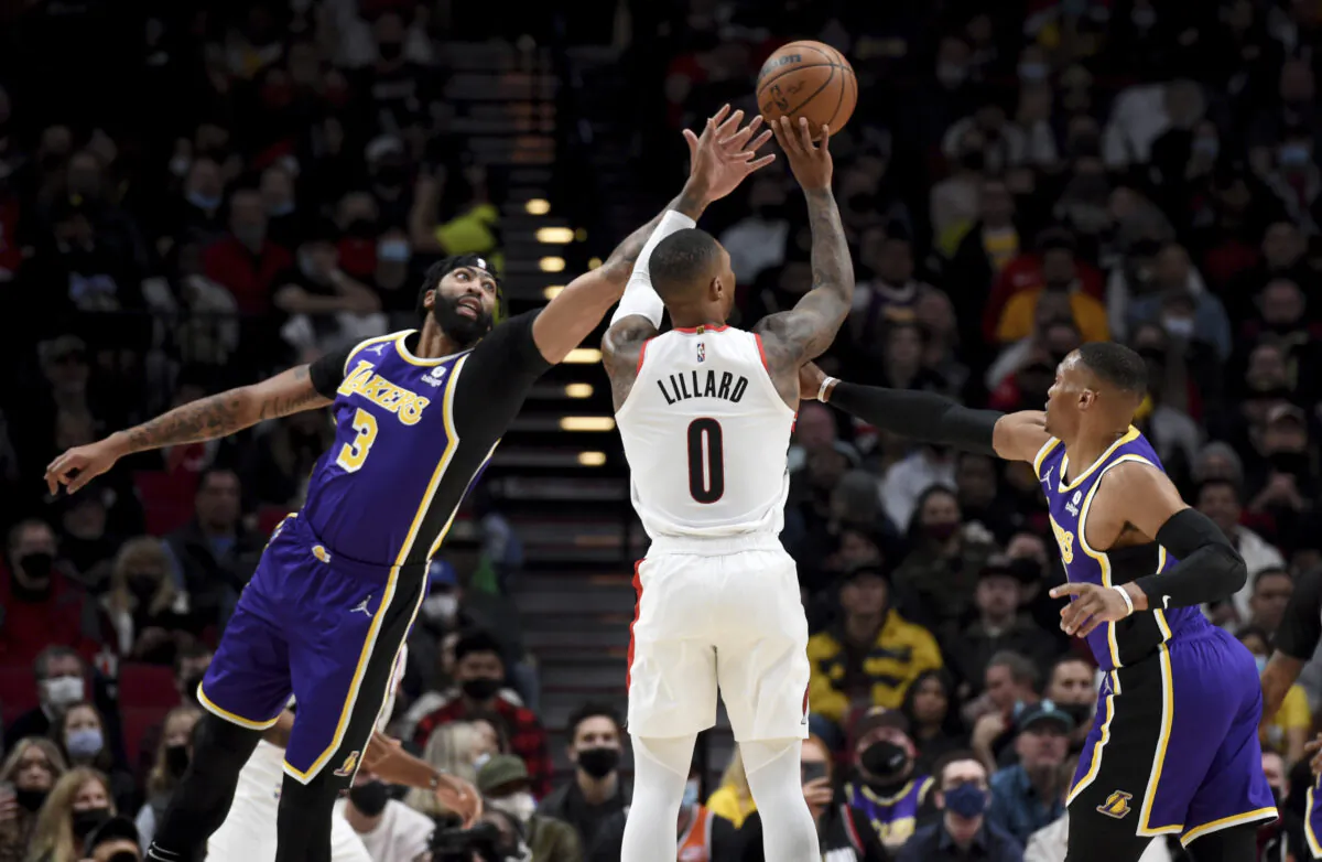 Portland Trail Blazers guard Damian Lillard, center, hits a 3-point shot from between Los Angeles Lakers Anthony Davis, left, and guard Russell Westbrook during the first half of an NBA basketball game in Portland, Ore., on Nov. 6, 2021. (AP Photo/Steve Dykes)
