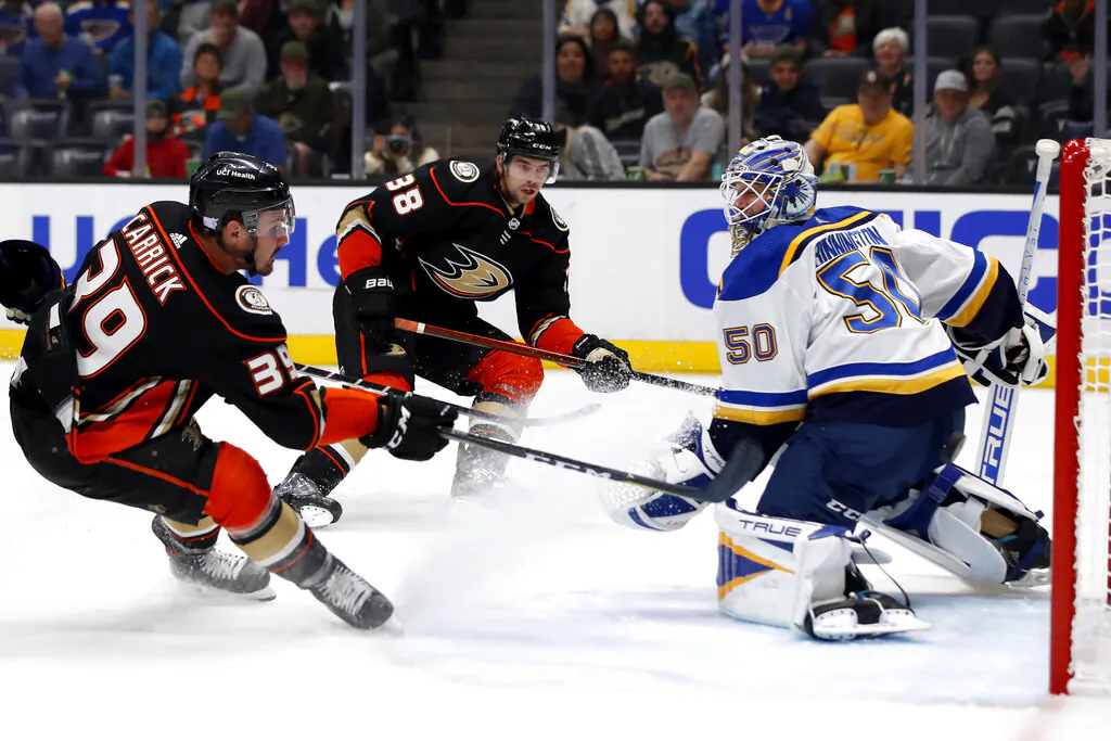 Anaheim Ducks center Sam Carrick (L) scores a goal against St. Louis Blues goaltender Jordan Binnington (R) on a pass by center Derek Grant (C) during the second period of an NHL hockey game in Anaheim, Calif., on Nov. 7, 2021. (Alex Gallardo/AP Photo)