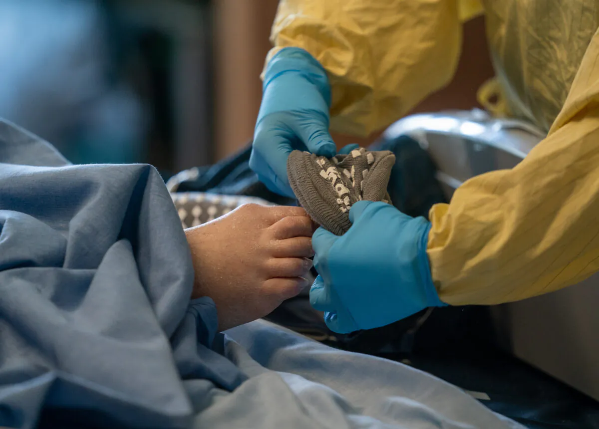A nurse puts a pair of socks on a patient in the COVID-19 Intensive Care Unit at Surrey Memorial Hospital in Surrey, B.C., on June 4, 2021. (The Canadian Press/Jonathan Hayward)