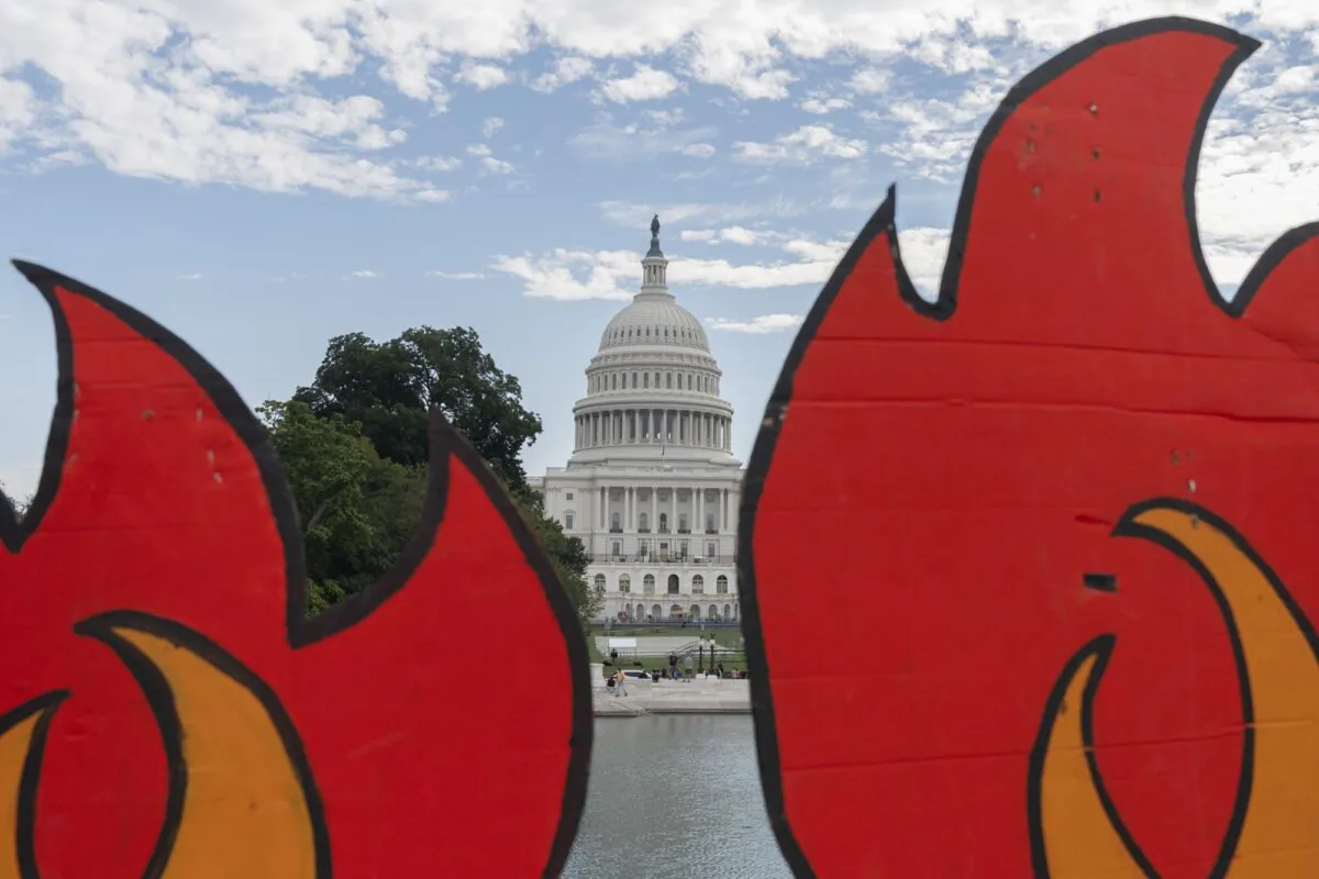 The U.S. Capitol seen between cardboard cutouts of flames during a climate change protest in Washington, D.C., on Oct. 15, 2021. (Jacquelyn Martin/AP Photo)