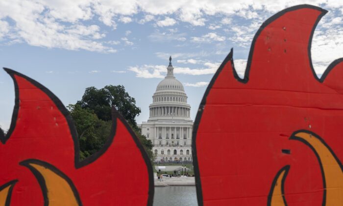 The U.S. Capitol seen between cardboard cutouts of flames during a climate change protest in Washington, on Oct. 15, 2021. (Jacquelyn Martin/AP Photo)