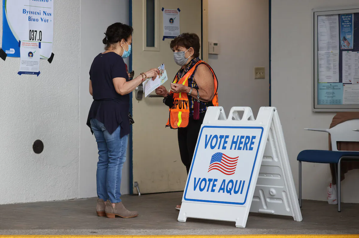 A poll worker speaks with a voter at the entrance to a polling station on Election Day in Miami Beach, Fla., on Nov. 2, 2021. (Joe Raedle/Getty Images)