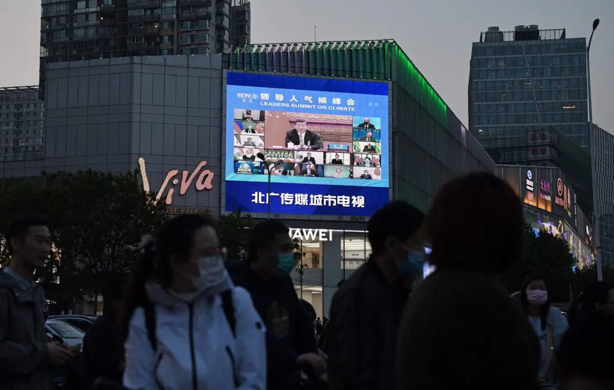 A news program reports on CCP leader Xi Jinping's appearance at a U.S.-led climate summit as seen on a giant screen in Beijing on April 23, 2021. (Greg Baker/AFP via Getty Images)