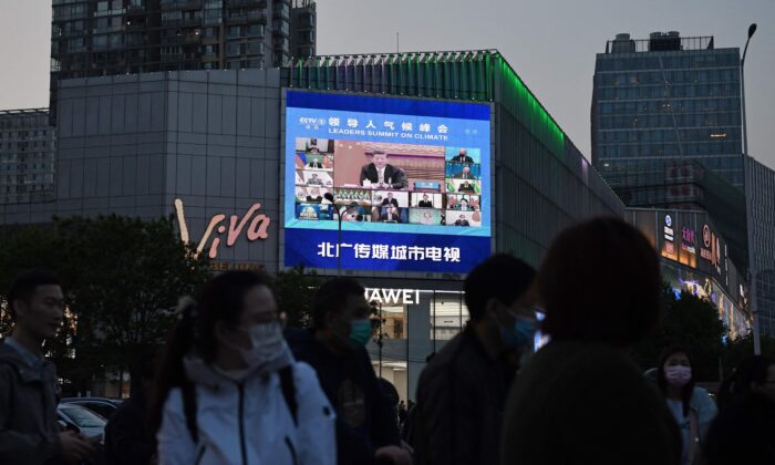 A news program reports on CCP leader Xi Jinping's appearance at a U.S.-led climate summit as seen on a giant screen in Beijing on April 23, 2021. (Greg Baker/AFP via Getty Images)