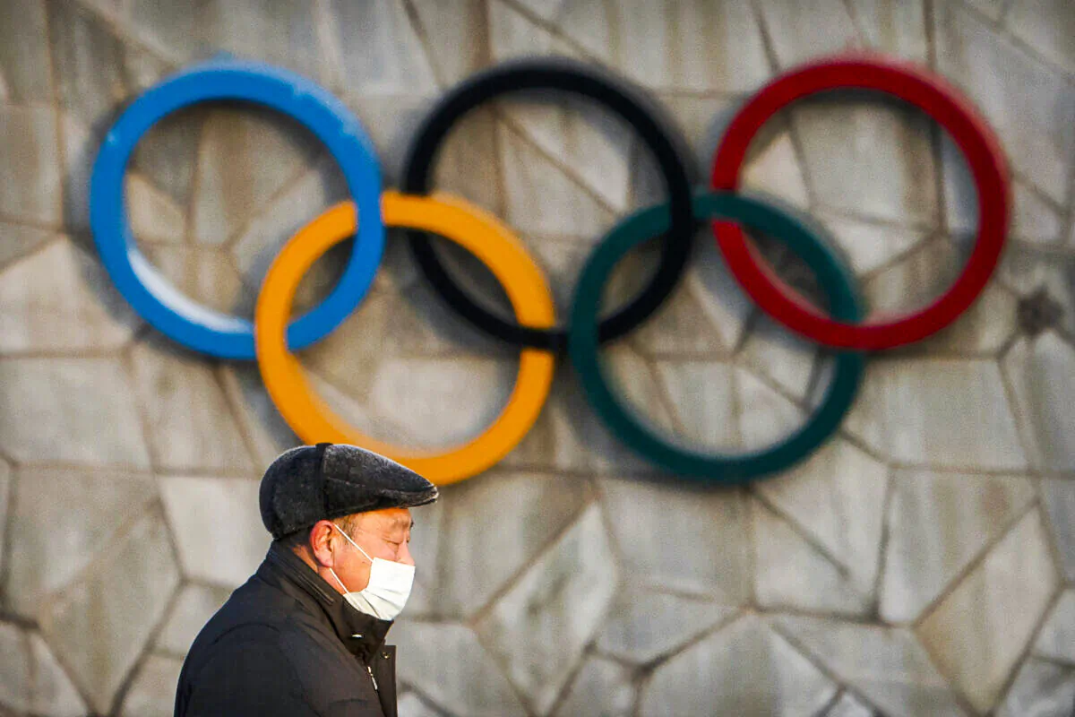 A man walks past the Olympic rings on the exterior of a venue for the upcoming 2022 Winter Olympics in Beijing on Feb. 2, 2021. (Mark Schiefelbein/AP Photo)