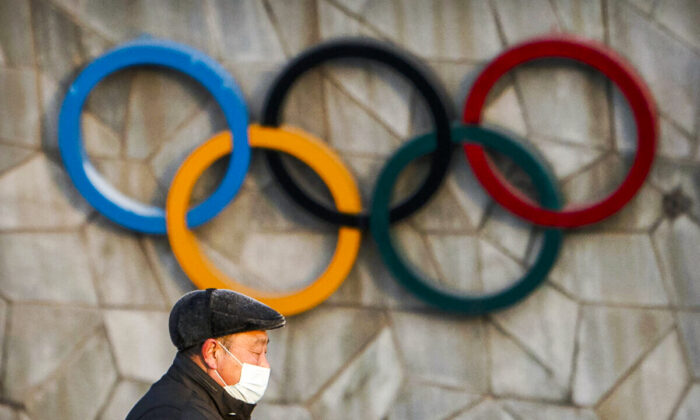 A man walks past the Olympic rings on the exterior of a venue for the upcoming 2022 Winter Olympics in Beijing on Feb. 2, 2021. (Mark Schiefelbein/AP Photo)