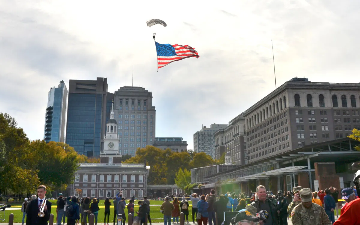 Two paratroopers jumped from a small airplane circling above Independence Mall, one of them holding a big American flag. They landed on the lawn next to the Liberty Bell during the 7th Annual Veterans Parade and Festival in Philadelphia, Pa., on Nov. 7, 2021. (Frank Liang/The Epoch Times)
