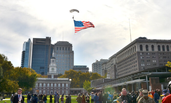 Two paratroopers jumped from a small airplane circling above Independence Mall, one of them holding a big American flag. y landed on the lawn next to the Liberty Bell during the 7th Annual Veterans Parade and Festival in Philadelphia, Pa., on Nov. 7, 2021. (Frank Liang/  Pezou)