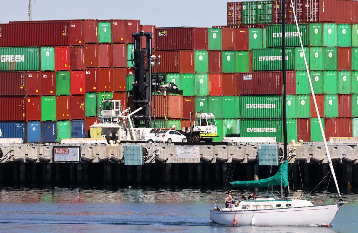 A sailboat passes cargo containers stacked at the Port of Los Angeles, the nation’s busiest container port, in San Pedro, Calif., on Oct. 15, 2021. (Mario Tama/Getty Images)