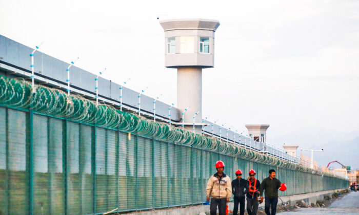 2018 年 9 月 4 日，工人们走过中国新疆地区达坂城职业技能教育中心的围栏。（Thomas Peter/路透社）