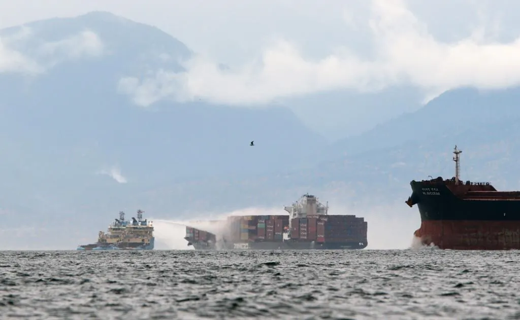Ships work to control a fire onboard the MV Zim Kingston about eight kilometres from the shore in Victoria, B.C., on  October 24, 2021. The container ship caught fire on Saturday and 16 crew members were evacuated and brought to Ogden Point Pier. (The Canadian Press/Chad Hipolito)