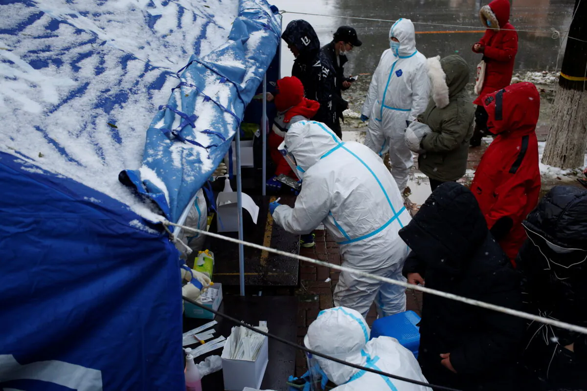 People line up for nucleic acid testing in the snow at a testing site in Dalian, Liaoning province, China, on Nov. 8, 2021. (cnsphoto via Reuters)