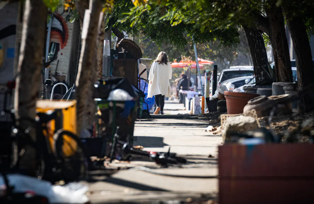 A woman walks in between a homeless encampment in Venice Beach, Calif., on Nov. 8, 2021. (John Fredricks/The Epoch Times)