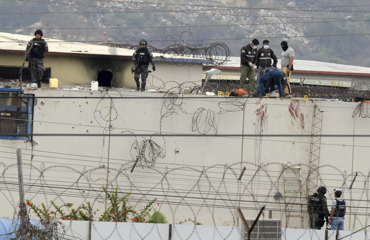 The body of a prisoner appears surrounded by police on the roof of the Litoral penitentiary the morning after riots broke out inside the jail in Guayaquil, Ecuador, on Nov. 13, 2021. (Jose Sanchez/AP Photo)