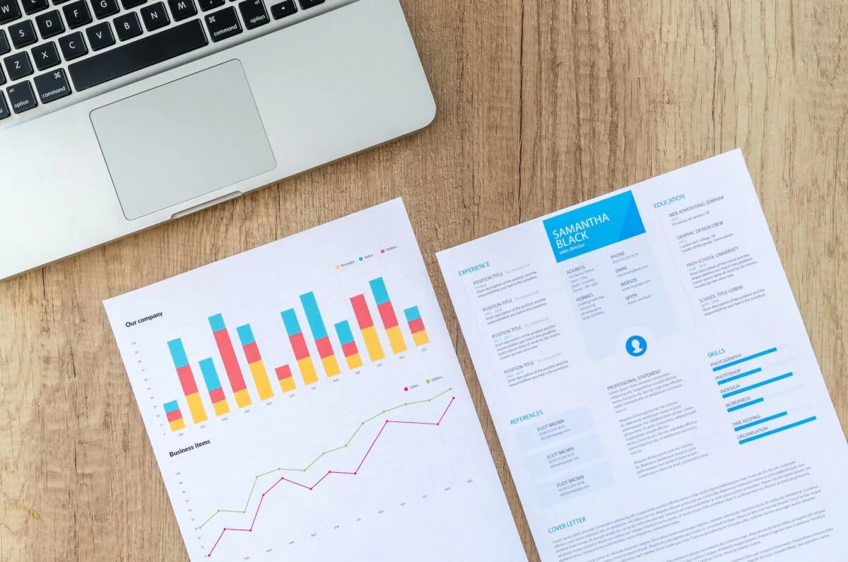 A resume and charts next to a laptop. (Lukas/Pexels)