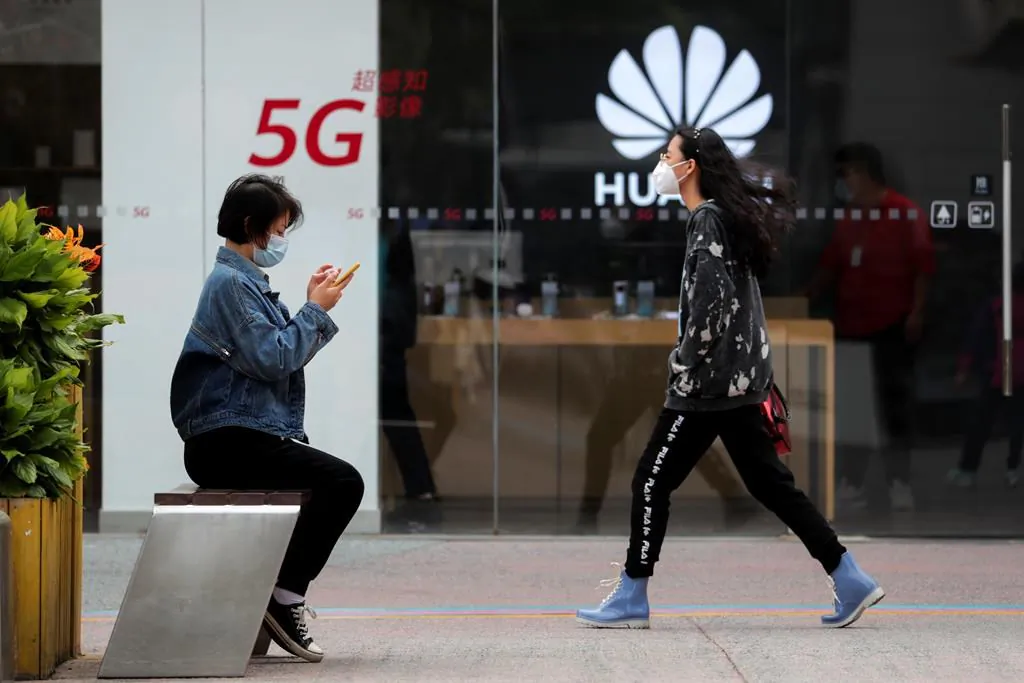 A woman walks by a Huawei retail shop in Beijing on Oct. 11, 2020. (AP Photo/Andy Wong, File)