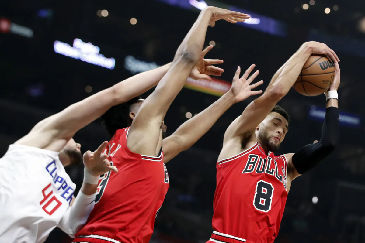 Chicago Bulls guard Zach LaVine, right, pulls down a rebound against Los Angeles Clippers center Ivica Zubac (40) and Bulls guard Devon Dotson, center, during the first half of an NBA basketball game in Los Angeles on Nov. 14, 2021. (AP Photo/Alex Gallardo)