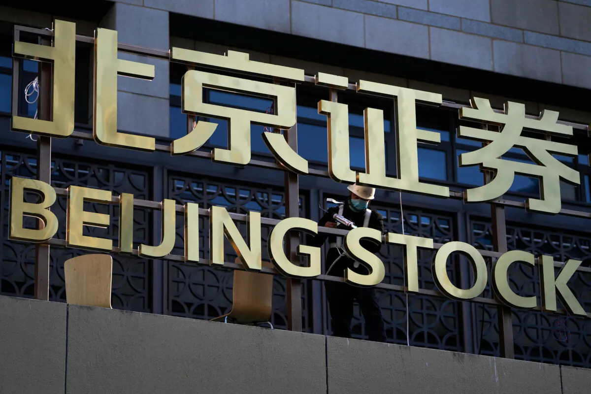 A worker installs the nameplate of Beijing Stock Exchange on the Financial Street in Beijing, on Nov. 14, 2021. (Andy Wong/AP Photo)
