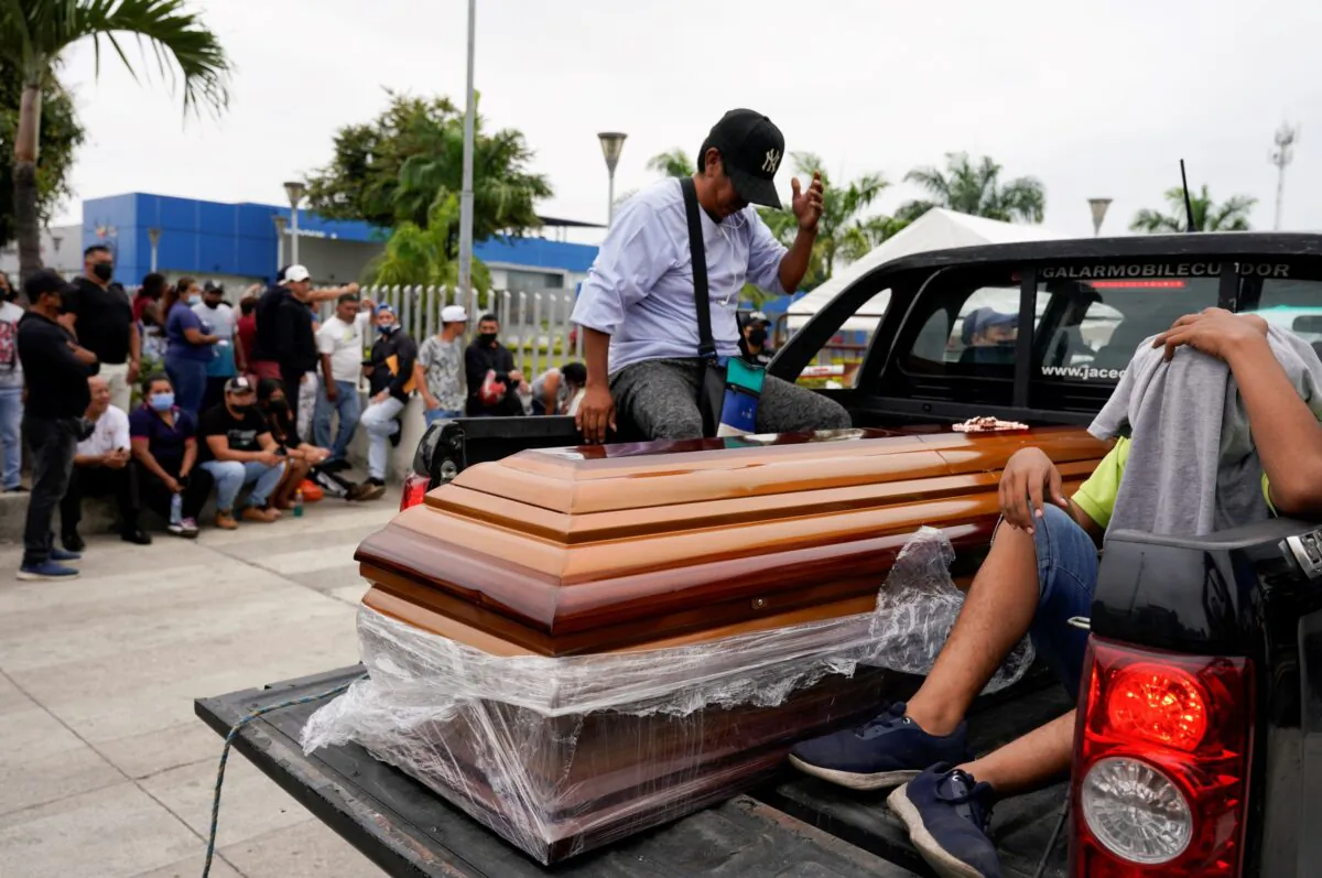 A casket is carried by a pickup truck as people gather outside the judicial police station after prisoners were killed and injured at the Penitenciaria del Litoral prison, in Guayaquil, Ecuador, on Nov. 14, 2021. (Santiago Arcos/Reuters)