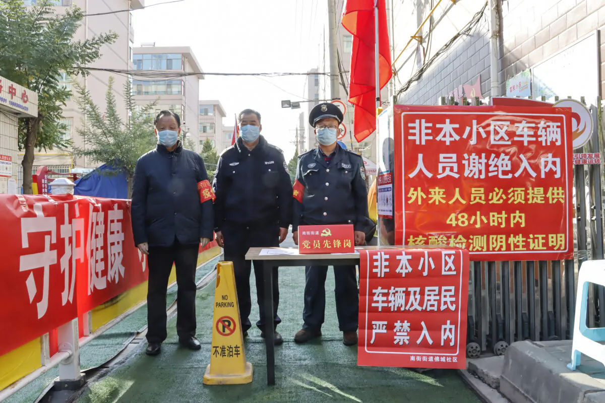 Security staff stand guard at the entrance of a residental area following Covid-19 cases in Zhangye in China's northwestern Gansu Province, on Oct. 23, 2021. (STR/AFP via Getty Images)