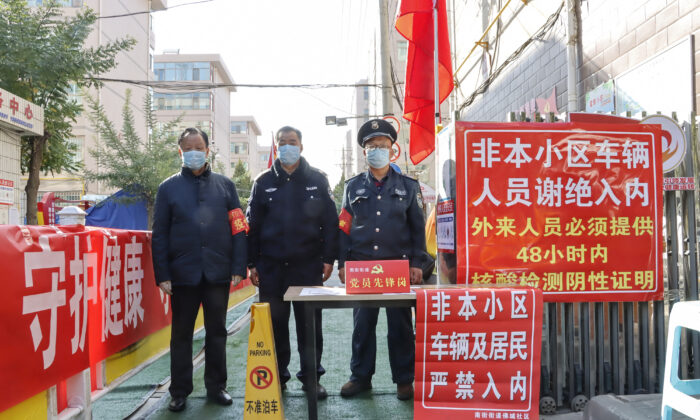2021 年 10 月 23 日，中国西北部甘肃省张掖市发生 Covid-19 病例后，安保人员在住宅区入口处站岗。（STR/AFP via Getty Images）