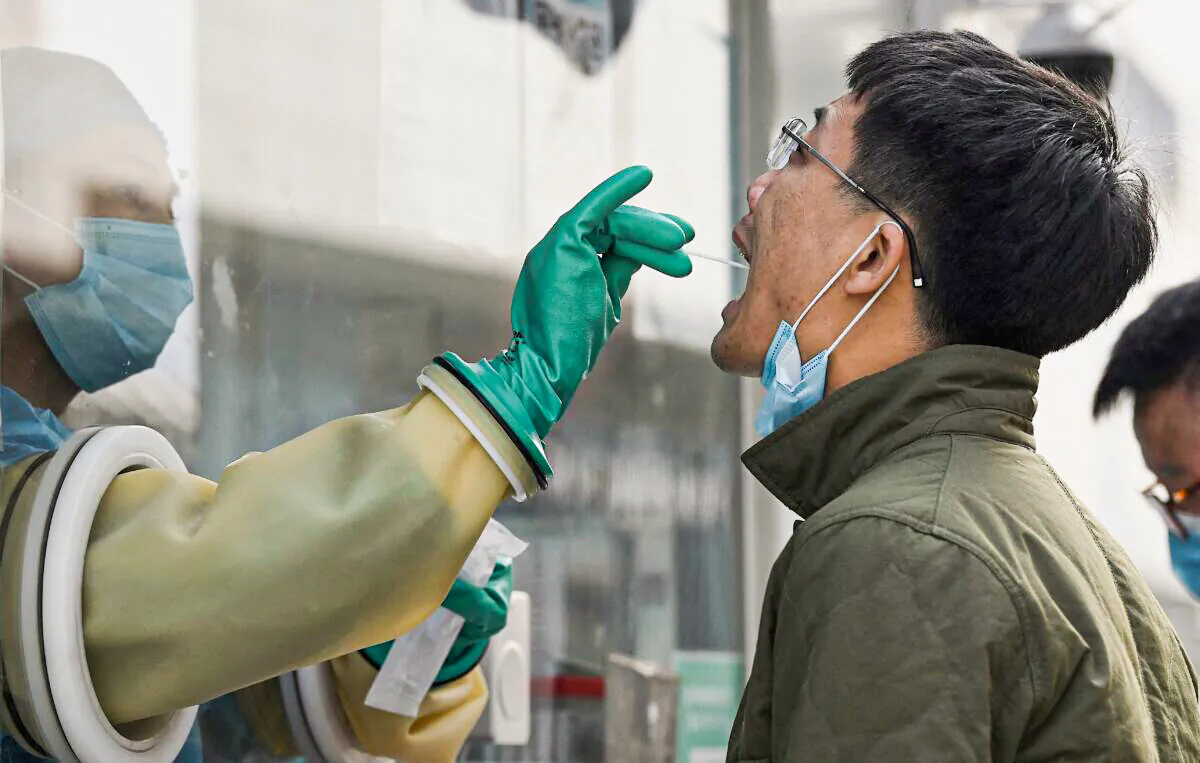 A health worker takes a swab for COVID-19 at a testing station in Beijing, China, on Oct. 25, 2021. (Noel Celis/AFP via Getty Images)