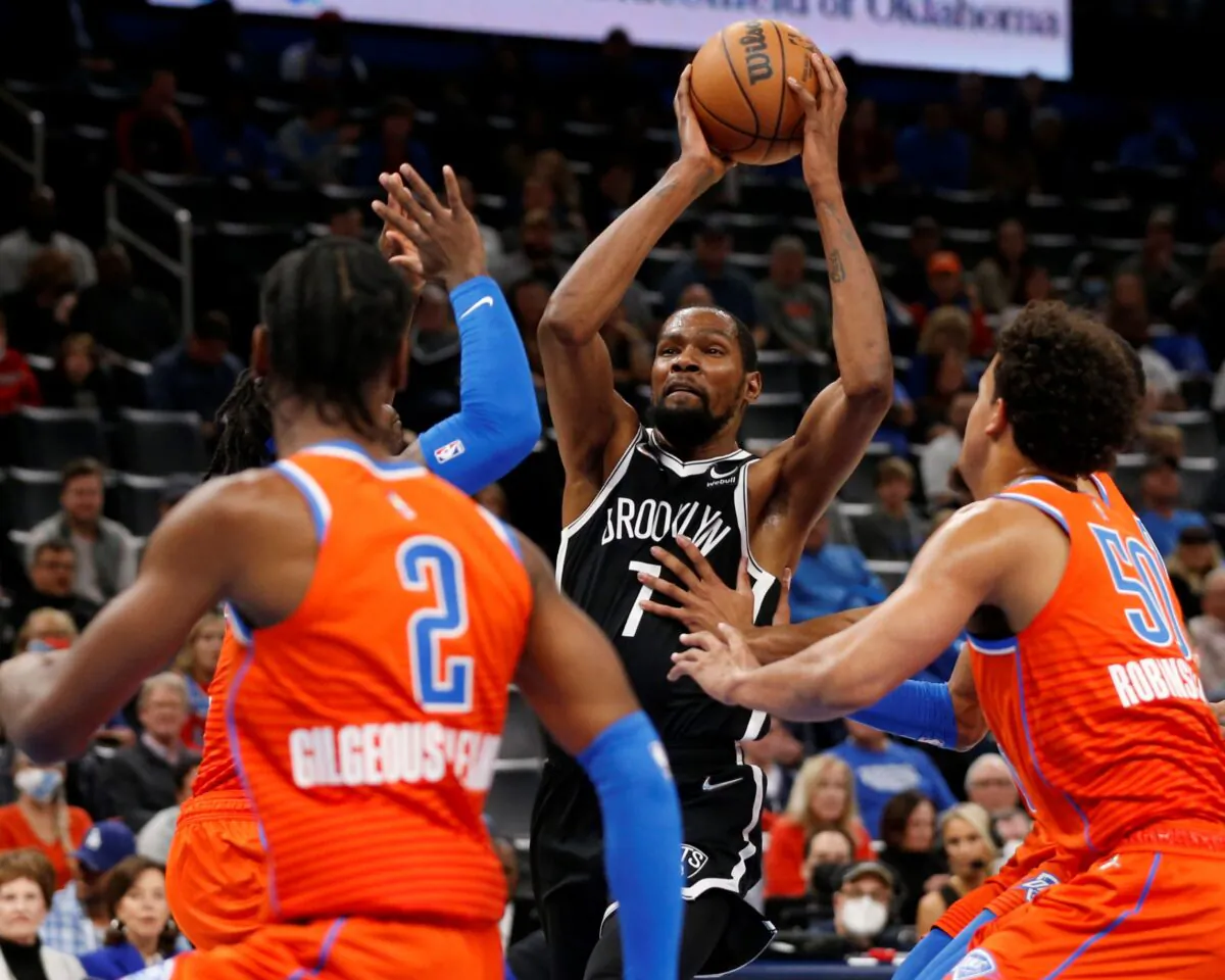 Brooklyn Nets forward Kevin Durant (7) goes against Oklahoma City Thunder guard Shai Gilgeous-Alexander (2), forward Jeremiah Robinson-Earl (50), and forward Luguentz Dort (5) during the first half of an NBA basketball game in Oklahoma City, on Nov. 14, 2021. (Garett Fisbeck/AP Photo)