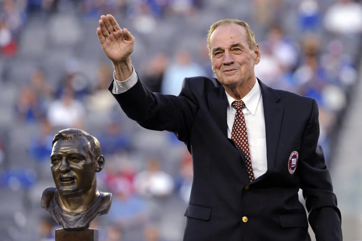 Former New York Giants linebacker Sam Huff waves to the fans as he stands behind his Hall of Fame bust during the halftime show of an NFL football game between the Giants and the Denver Broncos in East Rutherford, N.J., on Sept. 15, 2013. (Bill Kostroun/AP Photo)