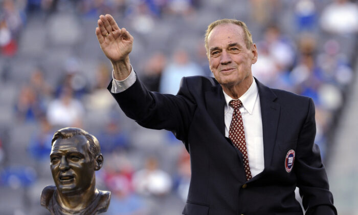 Former New York Giants linebacker Sam Huff waves to the fans as he stands behind his Hall of Fame bust during the halftime show of an NFL football game between the Giants and the Denver Broncos in East Rutherford, N.J., on Sept. 15, 2013. (Bill Kostroun/AP Photo)