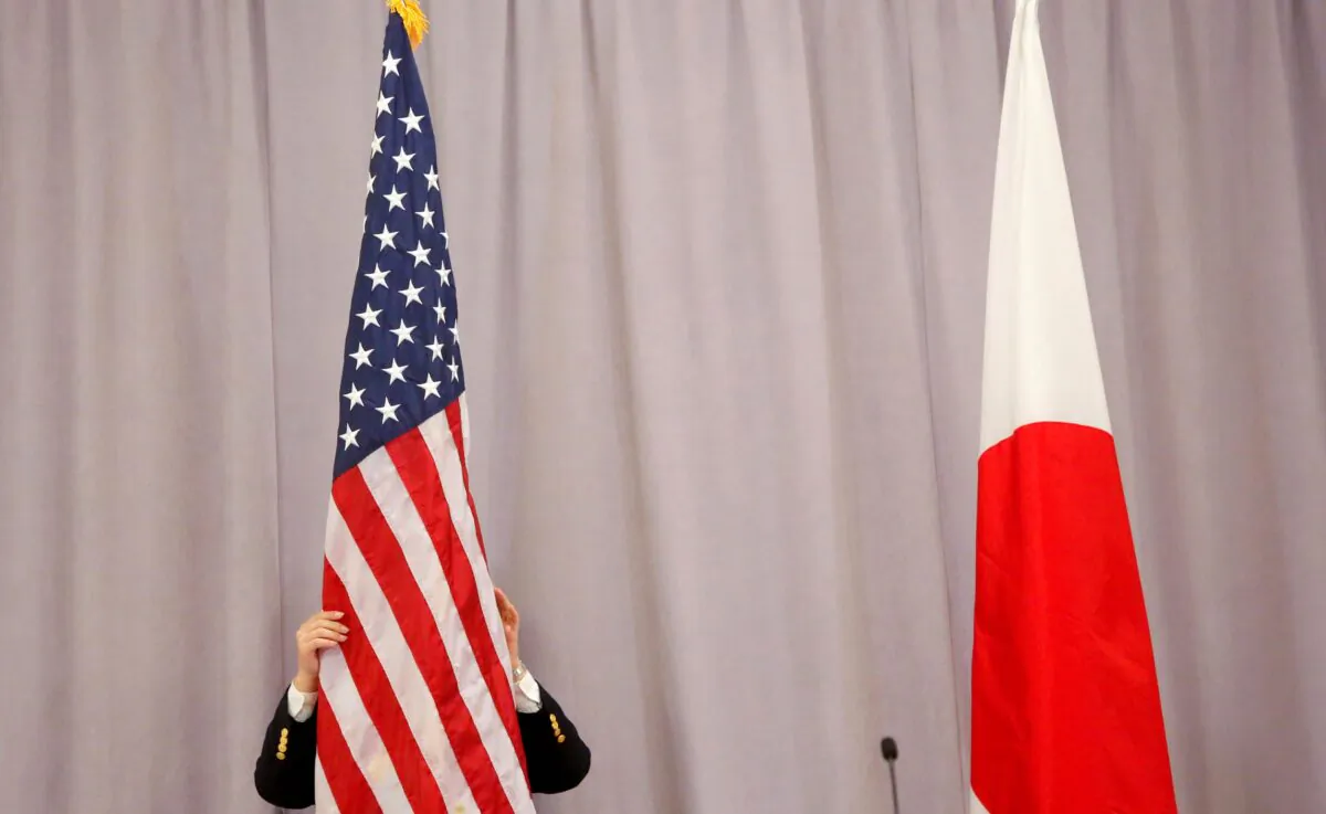 A worker adjusts the U.S. flag before Japanese Prime Minister Shinzo Abe addresses media following a meeting with President-elect Donald Trump in Manhattan, N.Y., on  Nov. 17, 2016. (Andrew Kelly/Reuters)