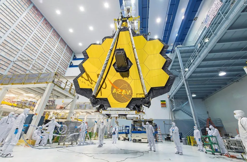 In this 2017 photo, technicians lift the mirror assembly of the James Webb Space Telescope using a crane inside a clean room at NASA's Goddard Space Flight Center in Greenbelt, Md. (NASA via AP/Desiree Stover)