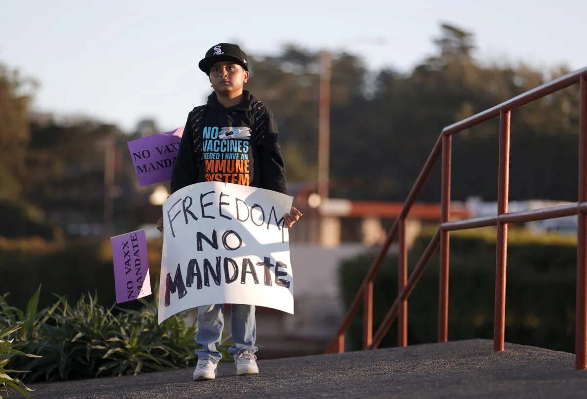 A young boy holds a sign during an anti-vaccination rally at the Golden Gate Bridge in San Francisco on Nov. 11, 2021. (Justin Sullivan/Getty Images)