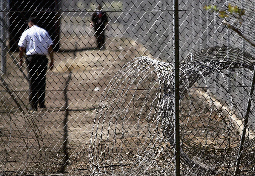 Security guards patrol the grounds near rolls of razor wire at the Villawood Immigration Detention Centre in Sydney, Australia, on Sept. 9, 2005. (Ian Waldie/Getty Images)