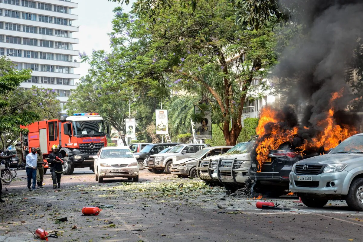 People extinguish fire on cars caused by a bomb explosion near the Parliament building in Kampala, Uganda, on Nov. 16, 2021. (Ivan/AFP via Getty Images)
