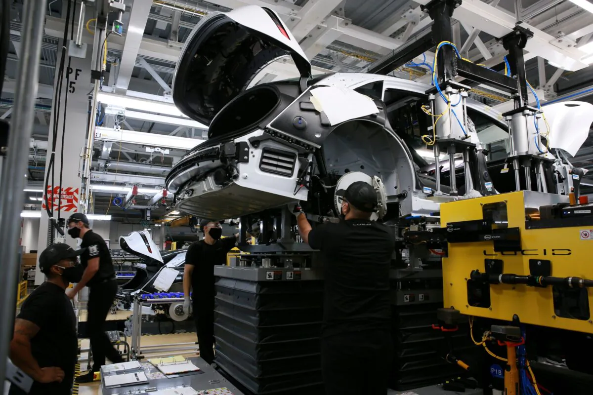 Workers marry the body structure with the battery pack and the front and rear sub frames as they assemble electric vehicles at the Lucid Motors plant in Casa Grande, Ariz., on Sept. 28, 2021. (Caitlin O'Hara/Reuters)