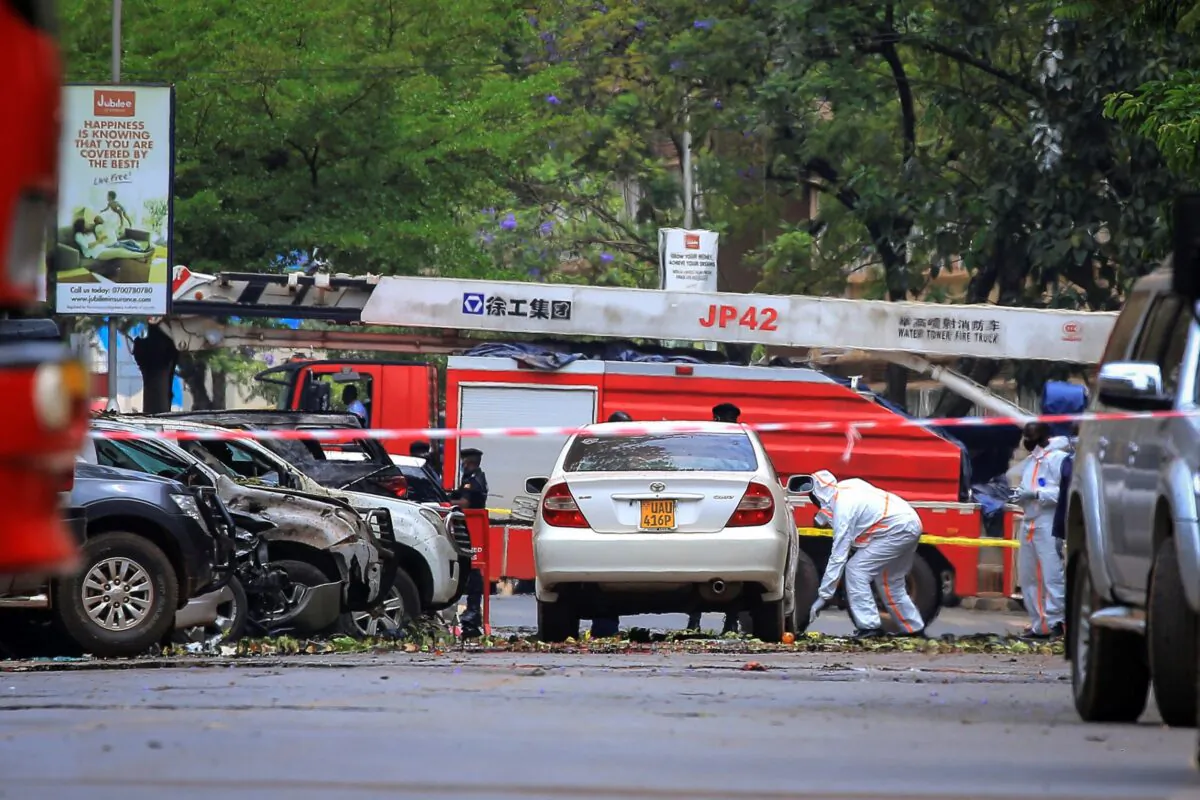 Security forces and forensics officers examine the scene of a blast on a street near the parliamentary building in Kampala, Uganda on Nov. 16, 2021. (Hajarah Nalwadda/AP Photo)