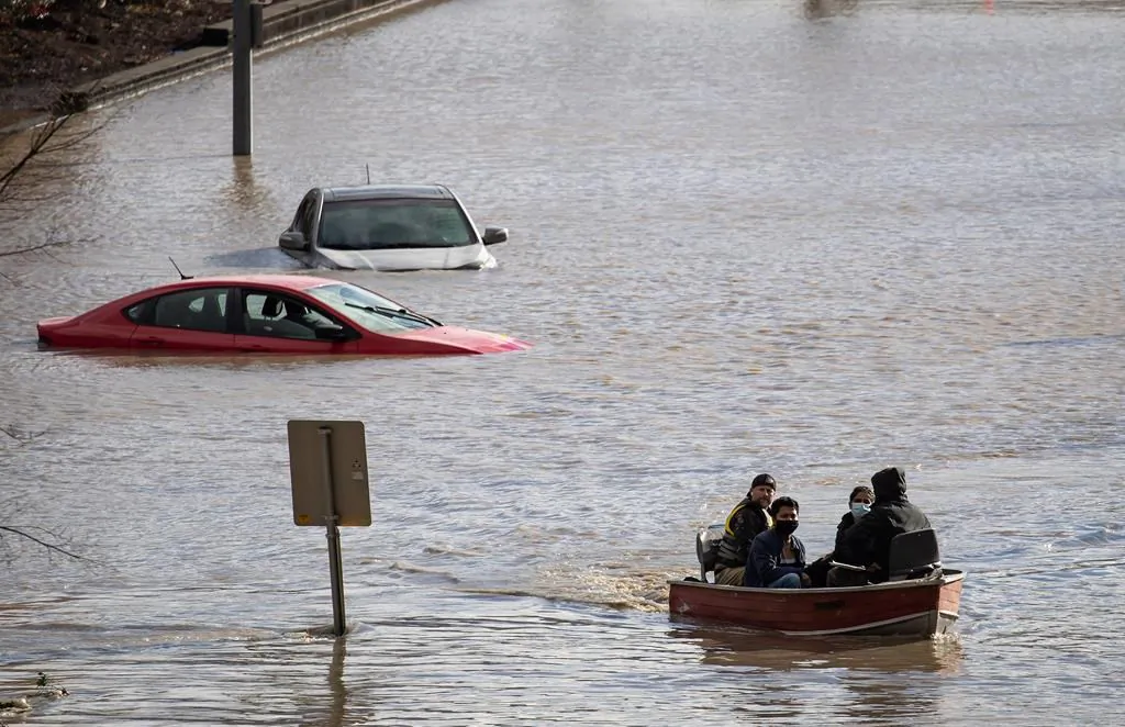 People who were stranded by high water due to flooding are rescued by a volunteer operating a boat in Abbotsford, B.C., November 16, 2021. (The Canadian Press/Darryl Dyck)