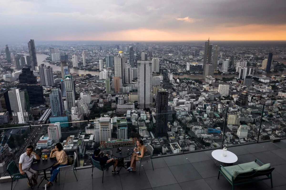 People sit in front of the Bangkok skyline on the observation deck of the King Power Mahanakhon skyscraper on Oct. 25, 2021. (Jack Taylor/AFP via Getty Images)