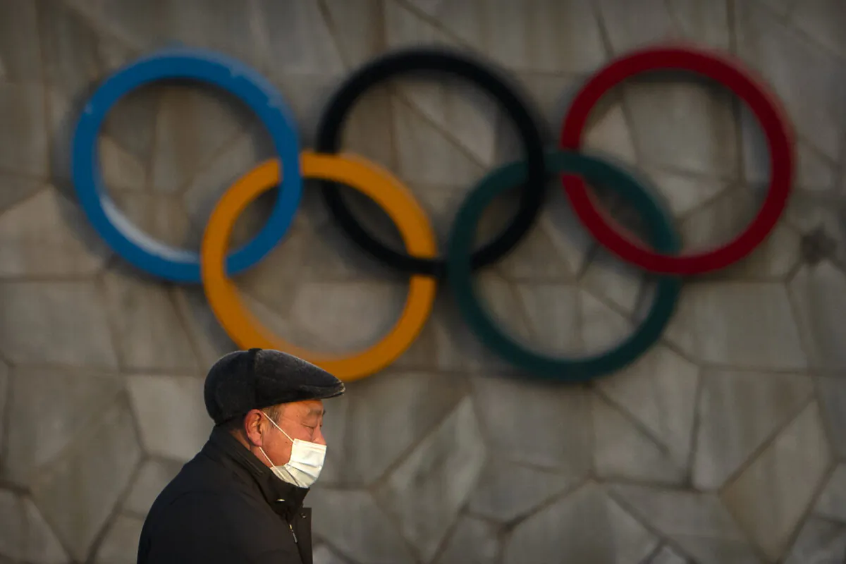 A man walks past the Olympic rings on the exterior of the National Stadium, also known as the Bird's Nest, which will be a venue for the upcoming 2022 Winter Olympics, in Beijing on Feb. 2, 2021. (Mark Schiefelbein/AP Photo)