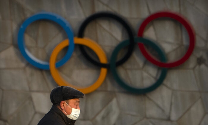 A man walks past the Olympic rings on the exterior of the National Stadium, also known as the Bird's Nest, which will be a venue for the upcoming 2022 Winter Olympics, in Beijing on Feb. 2, 2021. (Mark Schiefelbein/AP Photo)