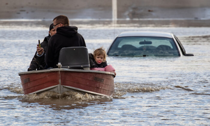 Residents stranded by high water due to flooding are rescued by a volunteer operating a boat, in Abbotsford, B.C., on Nov. 16, 2021. (The Canadian Press/Darryl Dyck)